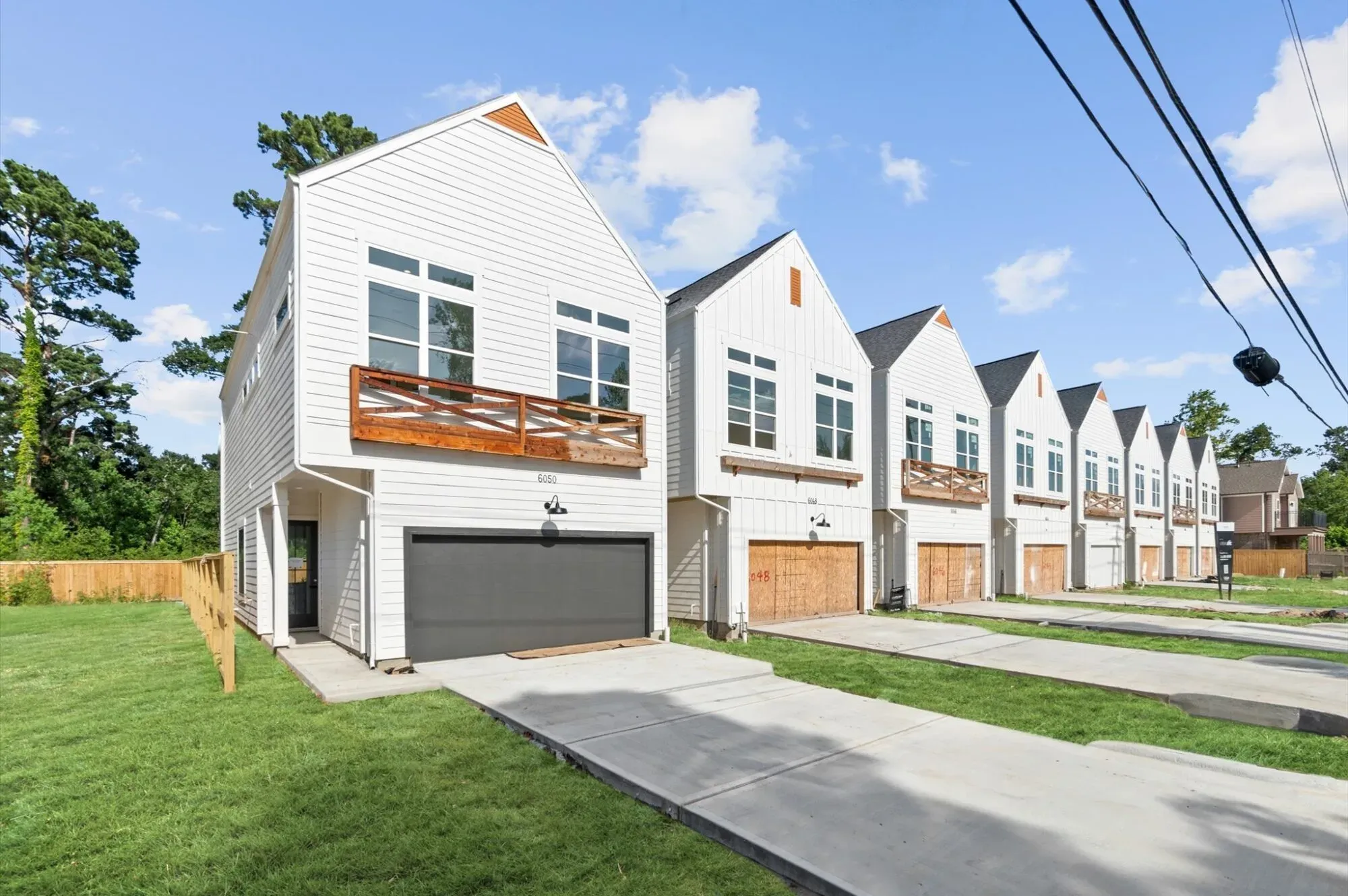 Row of white gabled townhomes with cedar balconies at Cebra Court