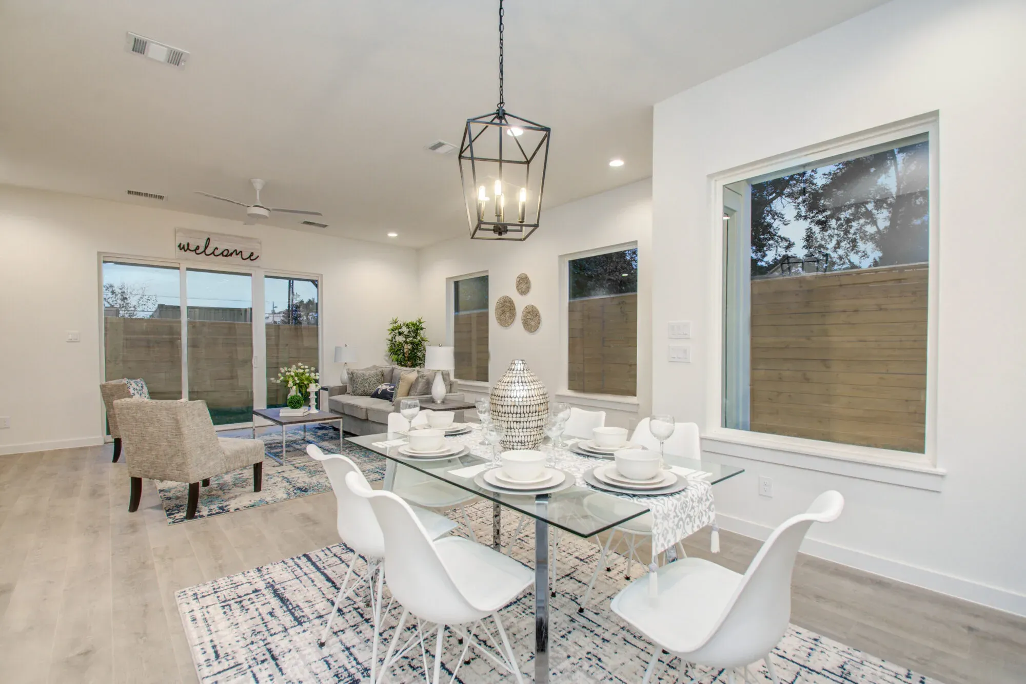 Open dining and living area with a lantern pendant and glass table